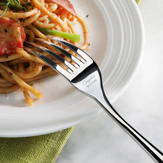 
                    
                      Fork resting on a white plate with spaghetti, tomato, and green vegetable on a green cloth.
                    
                  