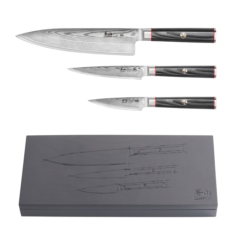 Three Damascus steel knives with black handles and red accents displayed above a gray box engraved with knife outlines.