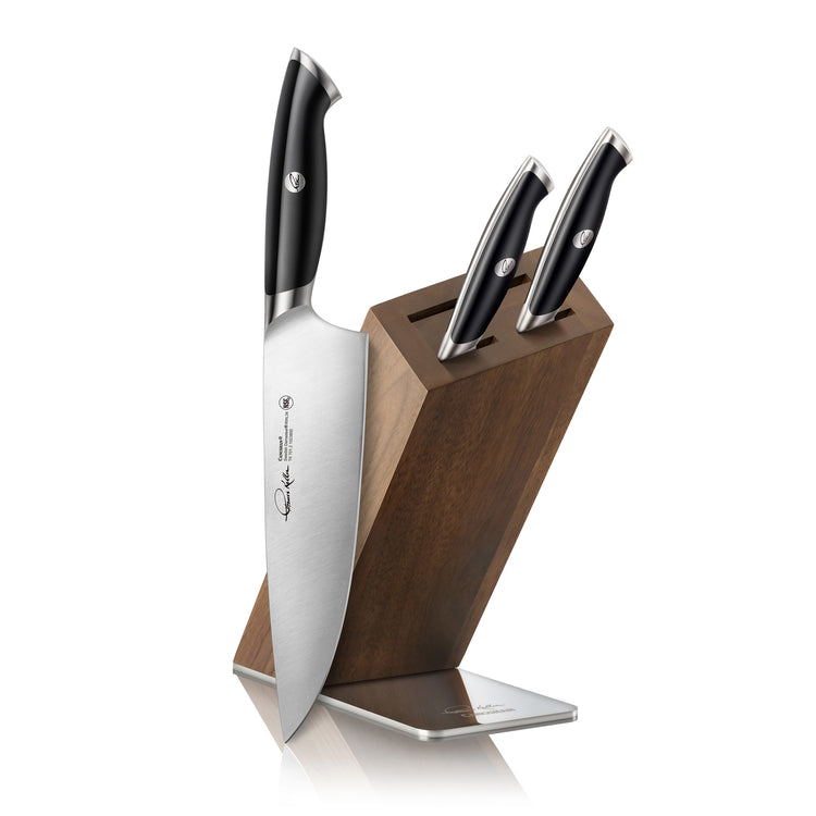 Four-piece knife set with black handles in a slanted Acacia wood block with stainless steel base.