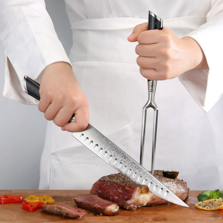 Hands holding a carving knife and fork cutting a cooked piece of meat on a wooden board with grilled vegetables.