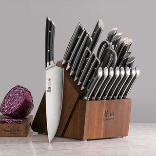 
                    
                      23-piece knife block set with black-handled knives and acacia wood block on marble surface.
                    
                  