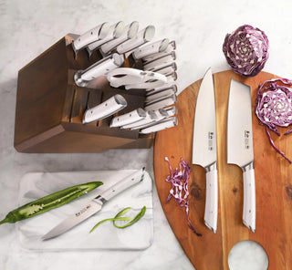 
                    
                      23-piece knife set with stainless steel blades and white handles in an acacia wood block, displayed with sliced vegetables.
                    
                  