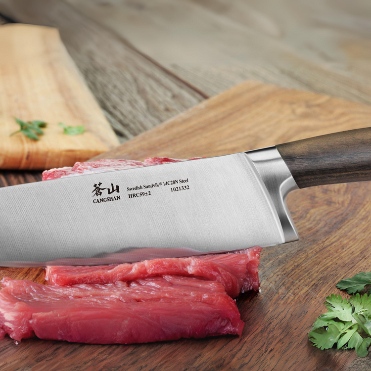 Knife with a walnut handle slicing raw meat on a wooden cutting board.