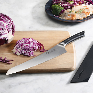 
                    
                      9-inch serrated deli knife with black handle on wooden cutting board next to sliced purple cabbage.
                    
                  