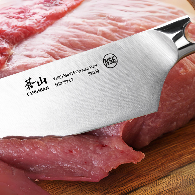 Close-up of a stainless steel knife blade cutting raw meat on a wooden surface, showing brand and steel type markings.