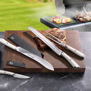 
                    
                      Six-piece BBQ knife set with white handles displayed on a wooden board with grilled meat and vegetables nearby.
                    
                  