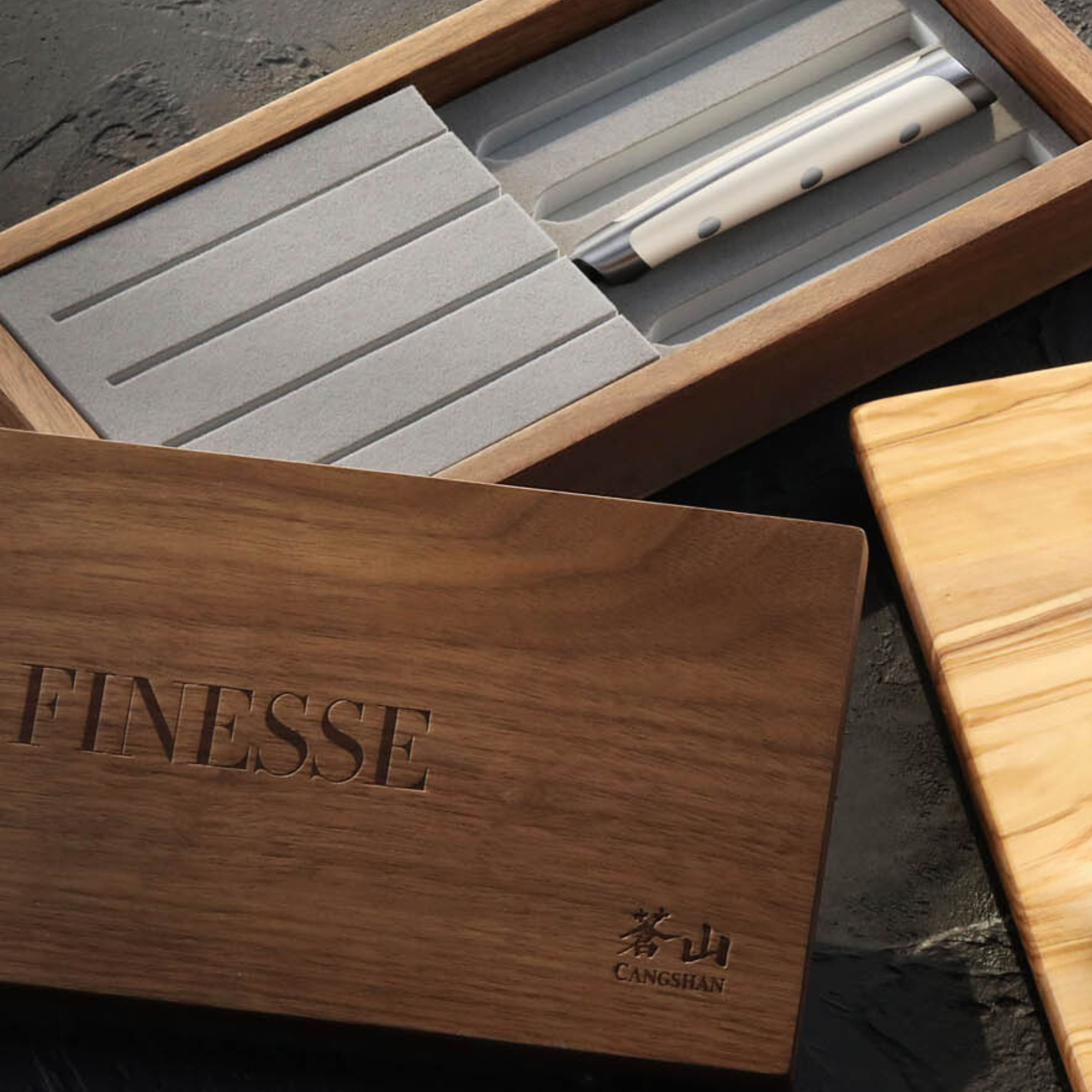 Four white-handled steak knives with straight edges in a walnut box labeled 