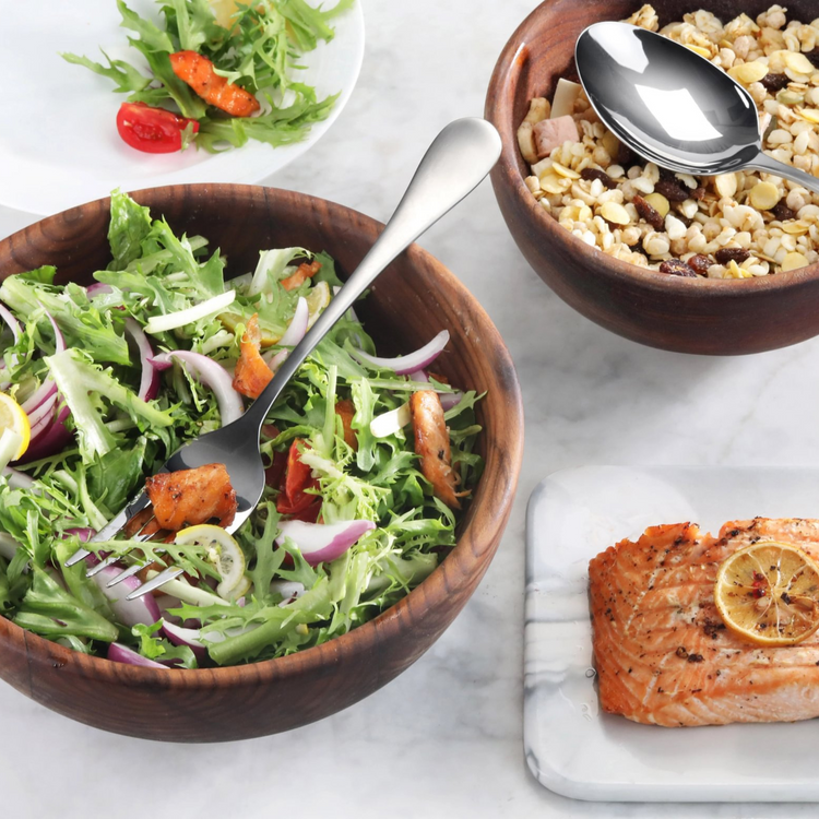 Serving fork with matte finish handle resting in a wooden bowl of mixed salad with grilled chicken pieces.