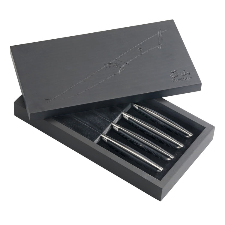 Four steak knives with polished metal handles in a partially open black presentation box with embossed design.