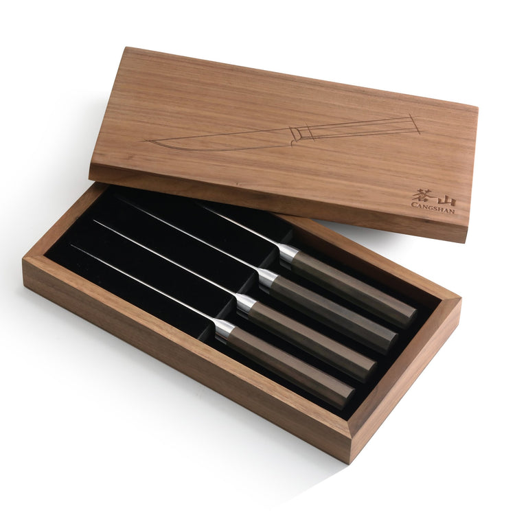 Four steak knives with dark handles arranged in a wooden box with a lid featuring a knife illustration.