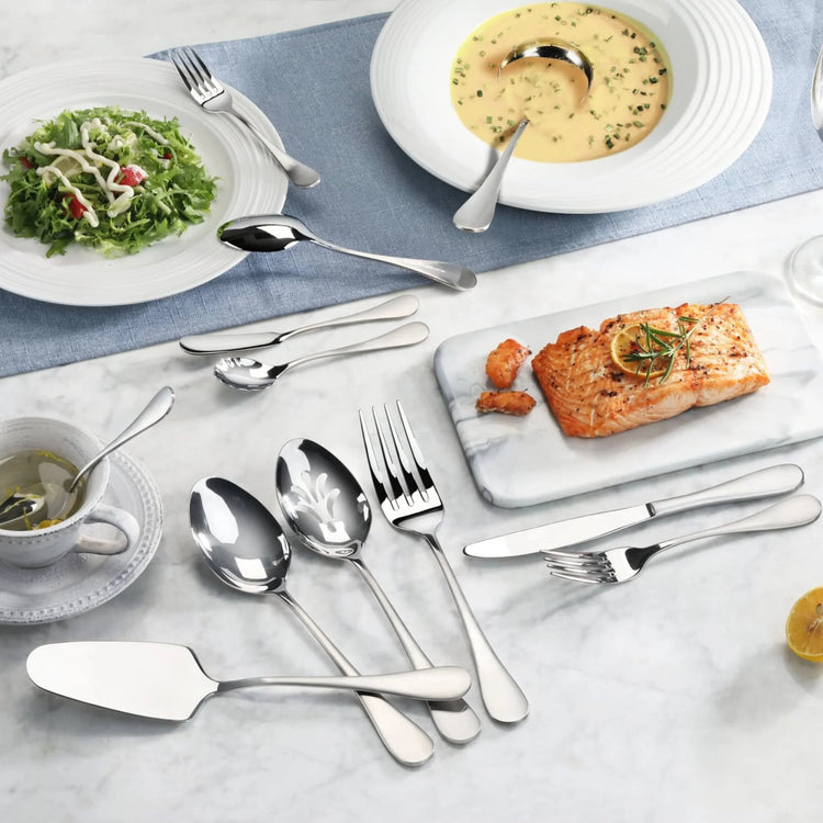 Stainless steel flatware with matte finish handles displayed with salad, soup, salmon, and tea on a marble table.