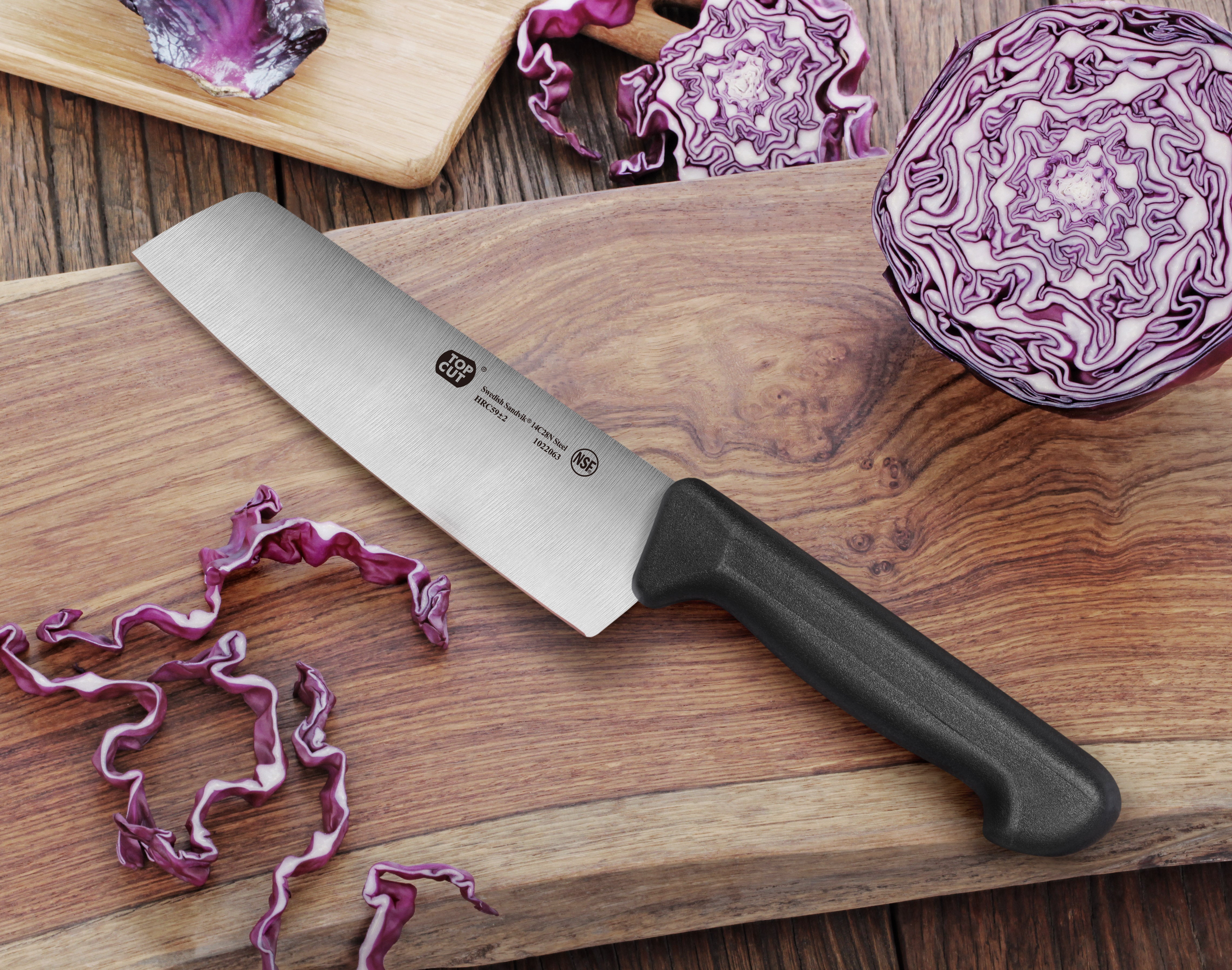 7-inch Nakiri vegetable cleaver with black handle on wooden cutting board next to sliced purple cabbage.