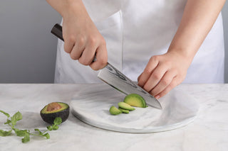 
                    
                      A person using the MAYA 5.5-inch Damascus steel prep utility knife to slice an avocado on a marble board.
                    
                  