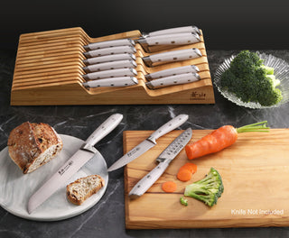 
                    
                      Bamboo knife organizer with 15 slots holding white-handled knives, next to cutting board with chopped carrot and broccoli.
                    
                  