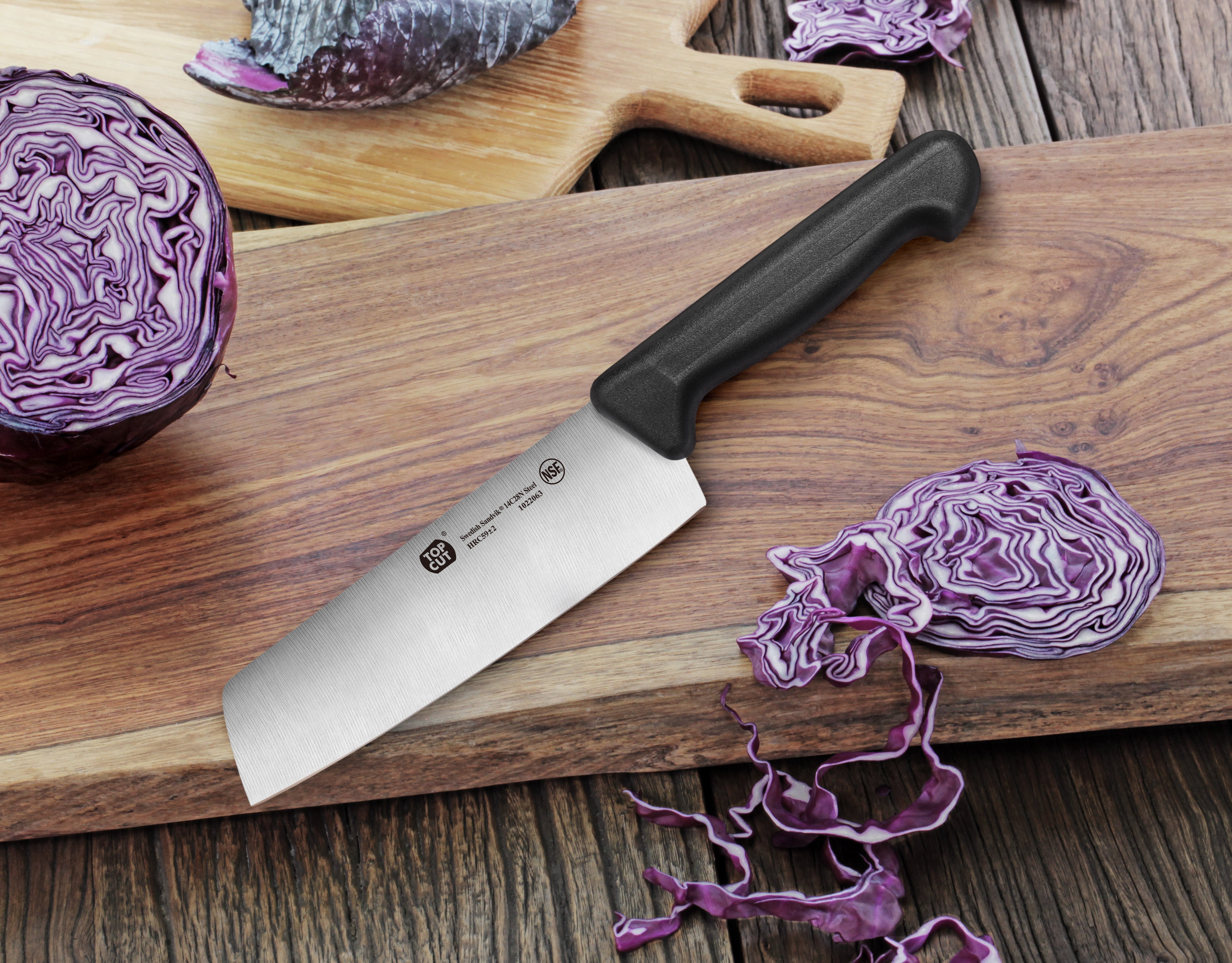 7-inch Nakiri vegetable cleaver with black handle on wooden cutting board, next to sliced purple cabbage.