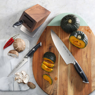 
                    
                      Four-piece knife set with black handles, wooden block, and sliced green squash on a wooden cutting board.
                    
                  