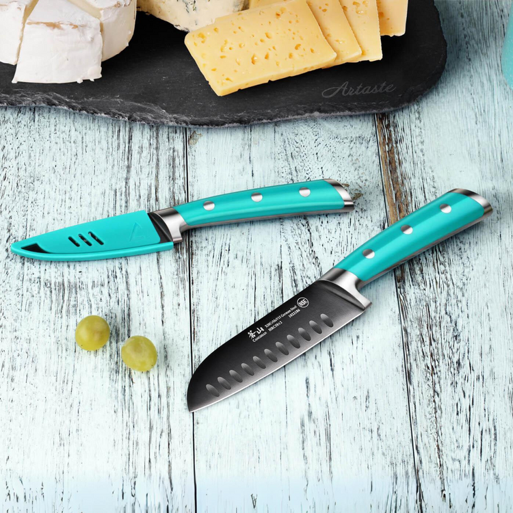 Two turquoise-handled kitchen knives on a light wooden surface with grapes and sliced cheese on a slate board.