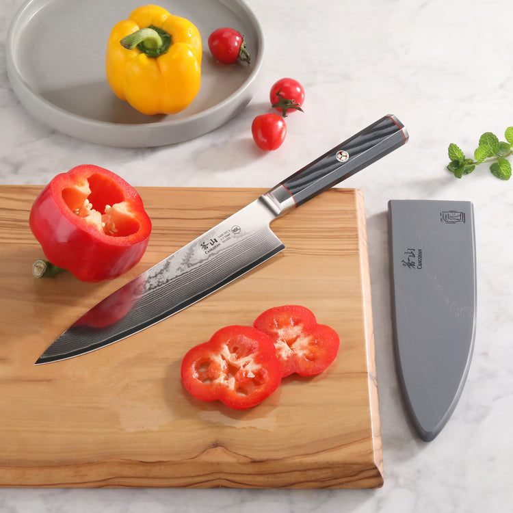 YARI Series 8-Inch Chef's Knife with black handle on wooden board, slicing red bell pepper, with sheath nearby.