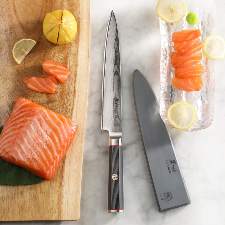8-inch sashimi knife with sheath beside sliced salmon, lemon wedges, and a wooden cutting board.