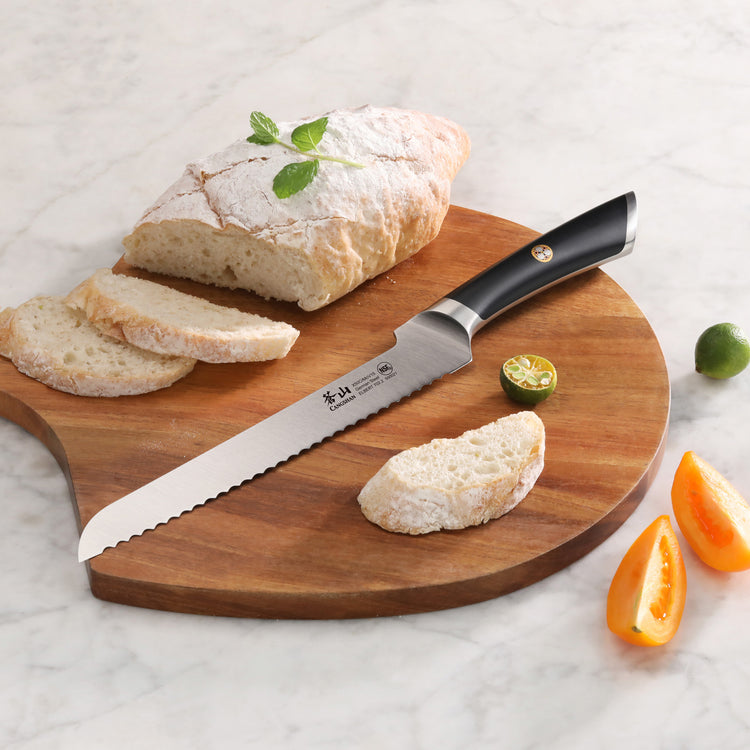8-inch serrated bread knife with black handle on wooden board next to sliced bread and citrus fruits.