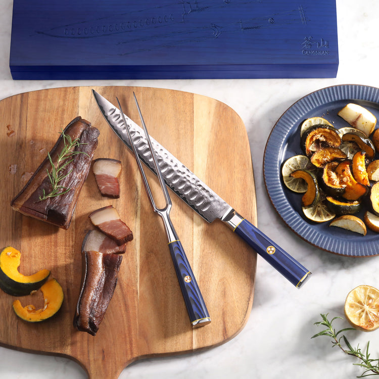 Blue-handled carving knife and fork on wooden board with sliced meat and roasted vegetables nearby.