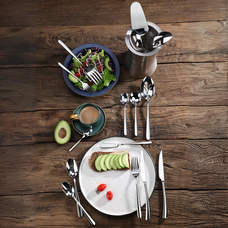 20-piece stainless steel flatware set displayed with a salad, avocado toast, coffee, and serving utensils on a wooden table.