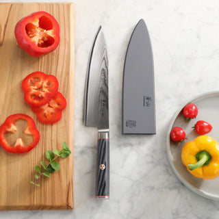 
                    
                      YARI Series 8-Inch Chef's Knife with sheath on marble surface, next to sliced red bell pepper on wooden board and yellow bell
                    
                  