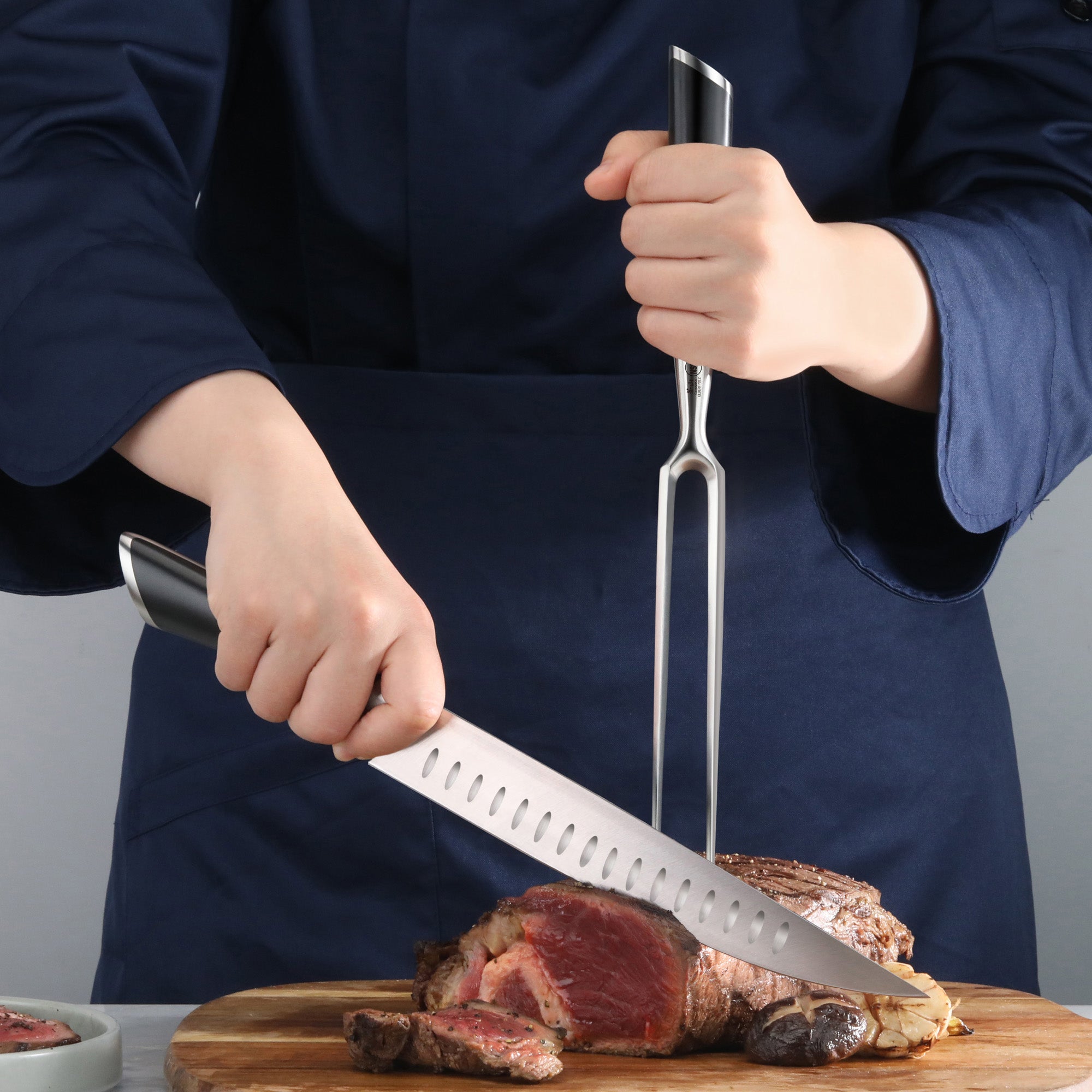 Person carving a medium-rare roast with a knife and fork on a wooden cutting board.