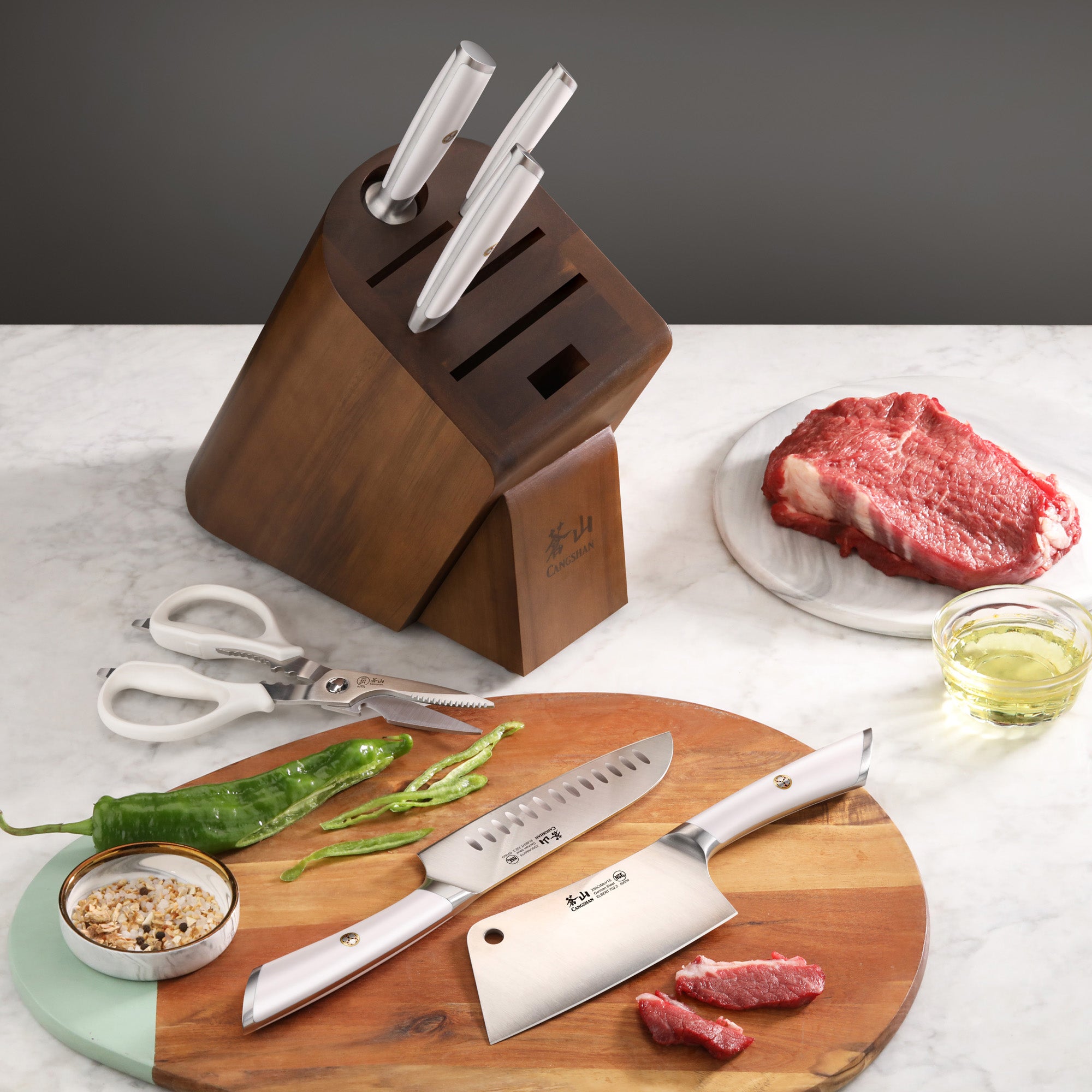Wooden knife block with three knives, kitchen scissors, a cutting board with sliced green peppers, a bowl of seasoning, raw s