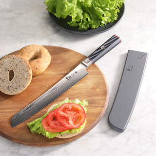 
                    
                      9-inch bread knife with Damascus steel blade and black handle on wooden board with sliced bagel, lettuce, tomato, and sheath.
                    
                  