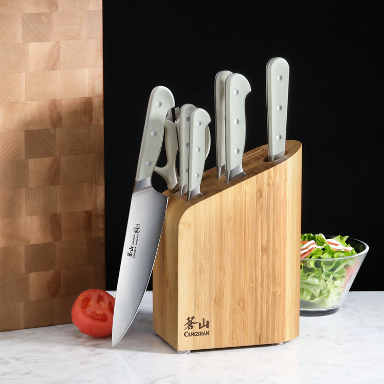 Knife block set with six white-handled knives in a bamboo block on a kitchen counter.