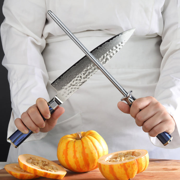 Person holding a diamond-coated honing steel and a chef's knife above a halved small pumpkin on a cutting board.