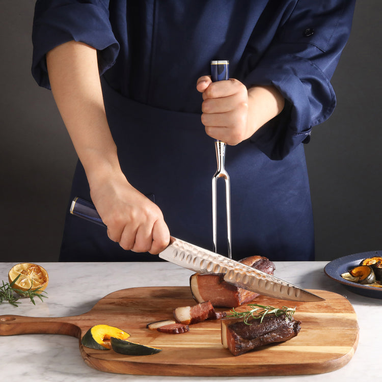 Person slicing cooked meat on a wooden cutting board with a carving knife and fork.