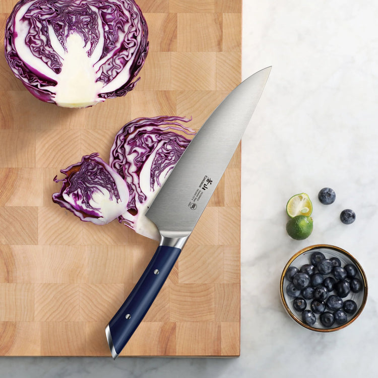 8-inch chef's knife with navy blue handle on wooden cutting board next to sliced purple cabbage and bowl of blueberries