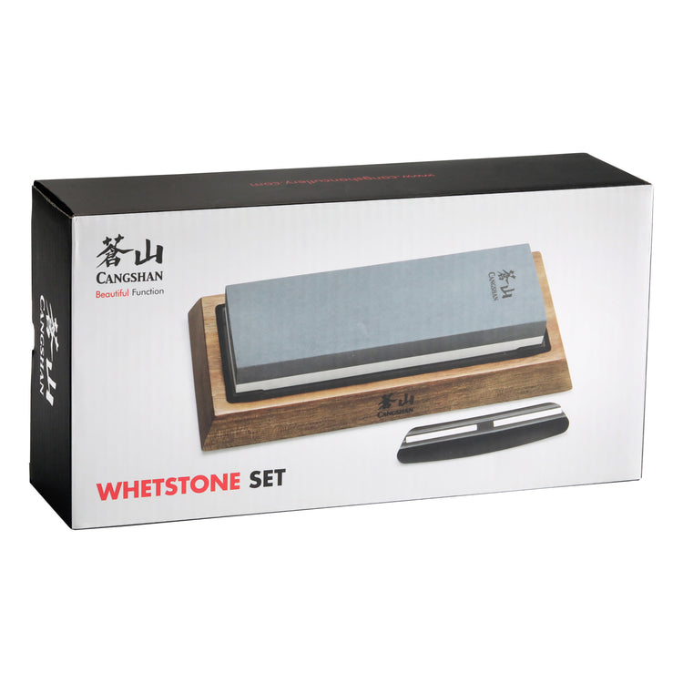 Dual-sided whetstone on wooden base with black knife sharpening guide beside it in product packaging box.