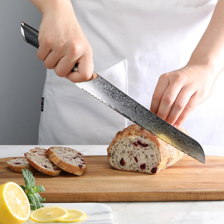 Hand holding a serrated knife slicing a loaf of bread with dried fruit on a wooden cutting board.