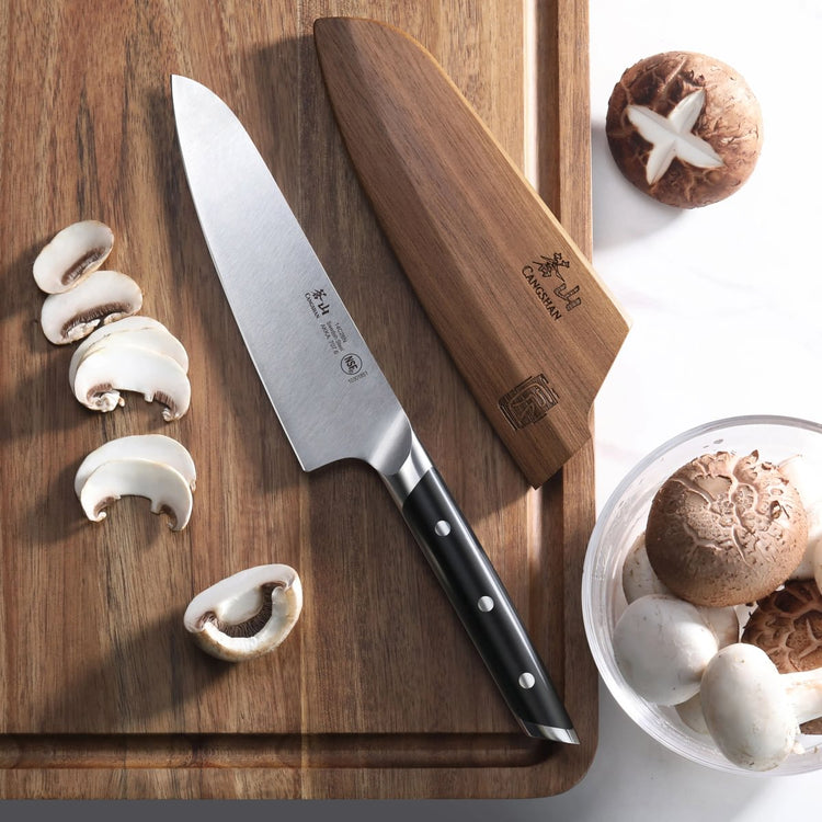 5.5-inch utility knife with black handle and wooden sheath on cutting board with sliced mushrooms.