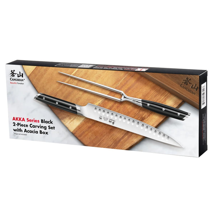 Two-piece carving set with a serrated knife and carving fork, both with black handles, displayed on a wooden board.