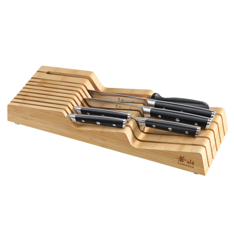 Seven kitchen knives with black handles arranged in a wooden in-drawer knife block with slots.