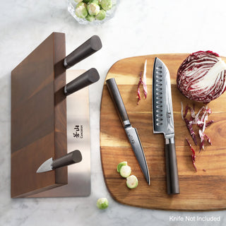 
                    
                      Magnetic wooden knife block holding three knives next to a cutting board with two knives and chopped vegetables.
                    
                  