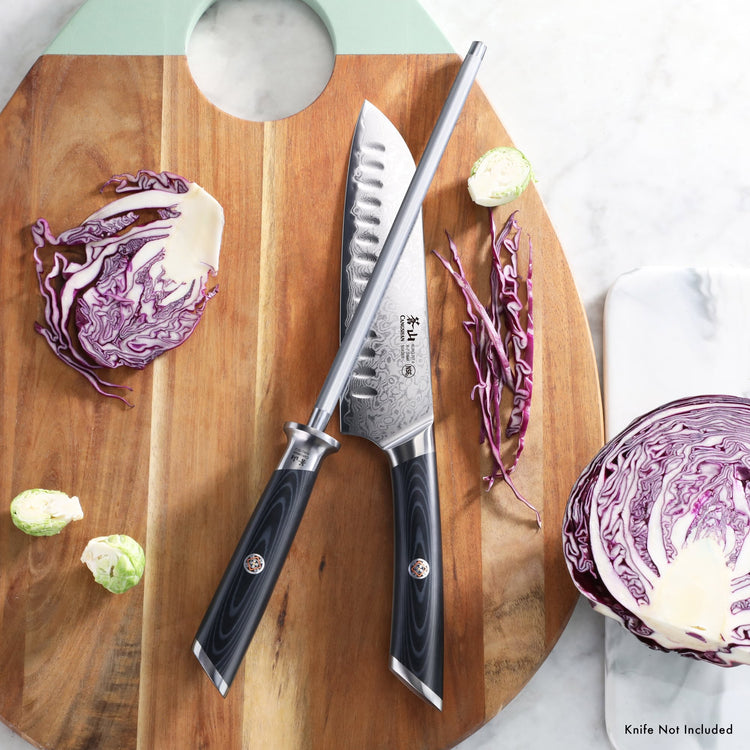 7-inch Santoku knife with black handle and sharpening steel on wooden cutting board with sliced purple cabbage.