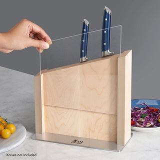 
                    
                      Hand lifting clear blade guard on maple magnetic knife block holding two knives with blue handles.
                    
                  