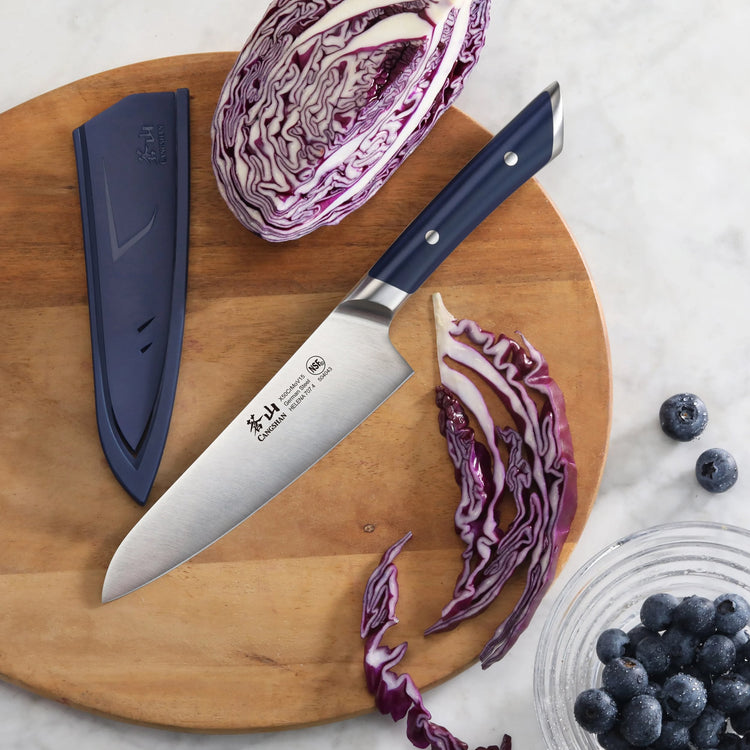 5.5-inch utility knife with blue handle on wooden cutting board, next to sliced purple cabbage and blueberries.