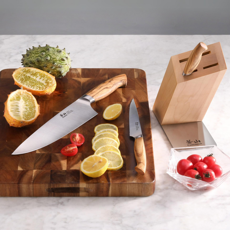 Four-piece knife block set with wooden handles, including chef and paring knives, on a wooden cutting board with sliced lemon