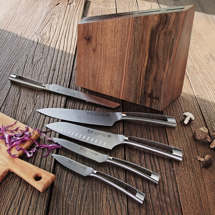 Six stainless steel knives with hollow handles displayed next to a walnut wood knife block on a wooden surface.