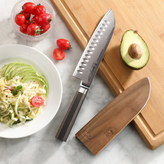 
                    
                      MAYA Series 7-inch Santoku Knife X-7 Damascus Steel with wooden sheath, avocado, and tomatoes on a cutting board.
                    
                  