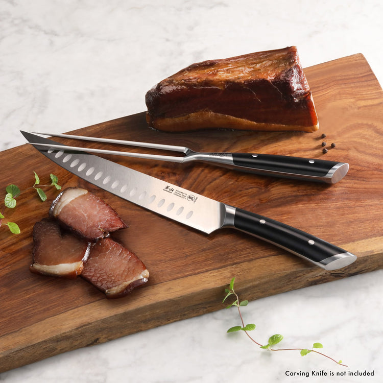 6-inch carving fork with black handle resting on a wooden cutting board next to sliced and whole smoked meat.