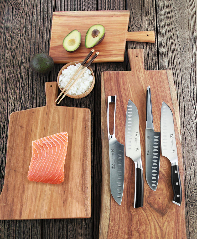 Four kitchen knives with black handles on a wooden board, next to salmon on a board and avocado with rice bowl.