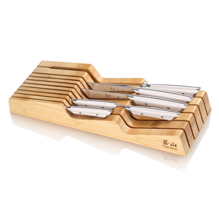 Seven stainless steel knives with metal handles arranged in a stepped bamboo drawer organizer tray.