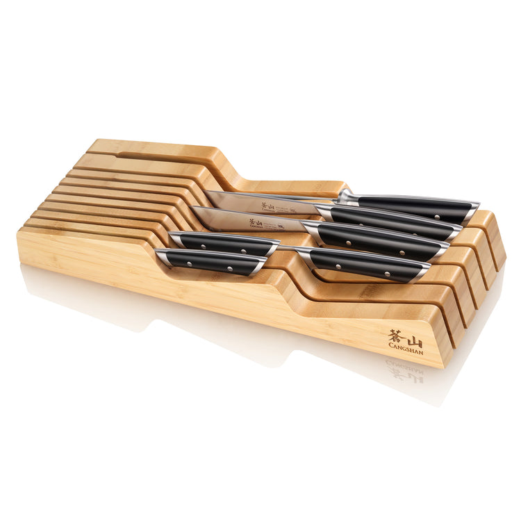 Seven knives with black handles arranged in a bamboo in-drawer knife tray with slots for each knife.